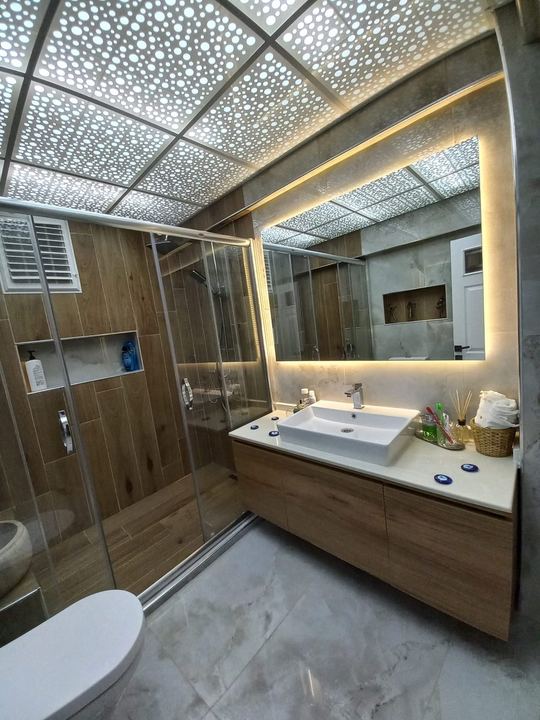 Ahşap ve mermer görünümlü fayanslı banyo, LED aydınlatmalı ayna ve lavabo dolabı